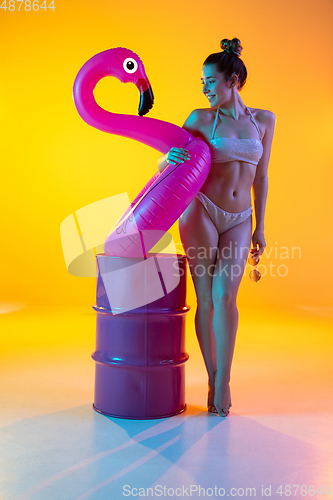 Image of Fashion portrait of seductive girl in stylish swimwear posing on a bright yellow background. Summertime, beach season