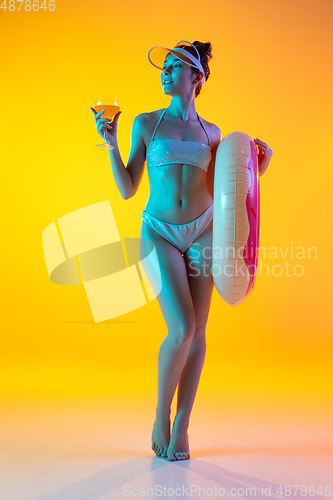 Image of Fashion portrait of seductive girl in stylish swimwear posing on a bright yellow background. Summertime, beach season