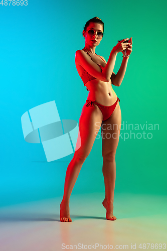 Image of Fashion portrait of seductive girl in stylish swimwear posing on a bright gradient background. Summertime, beach season