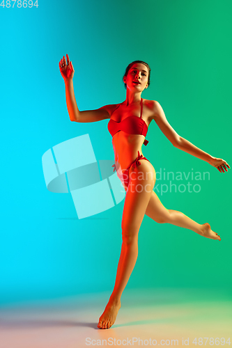 Image of Fashion portrait of seductive girl in stylish swimwear posing on a bright gradient background. Summertime, beach season