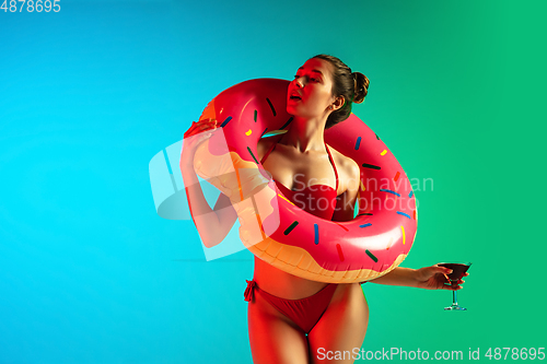 Image of Fashion portrait of seductive girl in stylish swimwear posing on a bright gradient background. Summertime, beach season