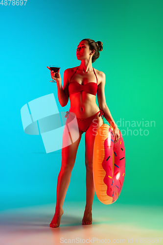 Image of Fashion portrait of seductive girl in stylish swimwear posing on a bright gradient background. Summertime, beach season