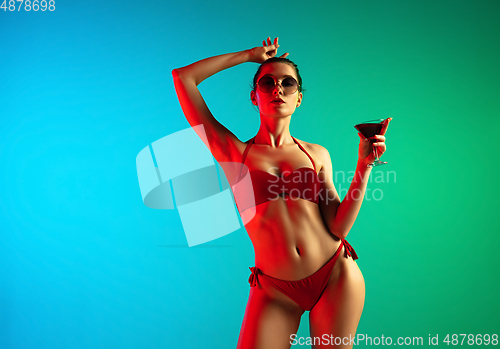 Image of Fashion portrait of seductive girl in stylish swimwear posing on a bright gradient background. Summertime, beach season