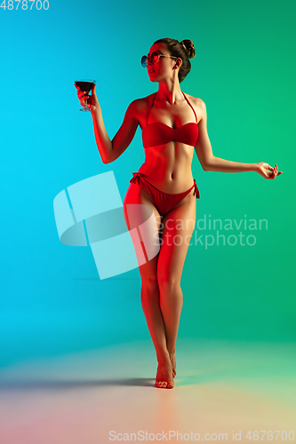 Image of Fashion portrait of seductive girl in stylish swimwear posing on a bright gradient background. Summertime, beach season