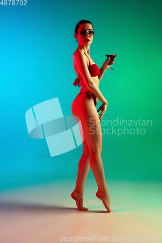 Image of Fashion portrait of seductive girl in stylish swimwear posing on a bright gradient background. Summertime, beach season