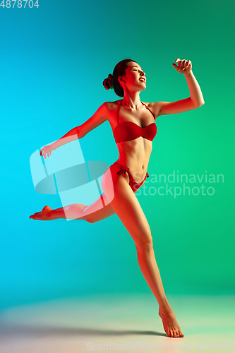 Image of Fashion portrait of seductive girl in stylish swimwear posing on a bright gradient background. Summertime, beach season