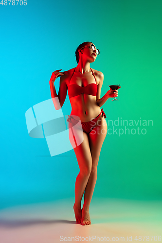 Image of Fashion portrait of seductive girl in stylish swimwear posing on a bright gradient background. Summertime, beach season