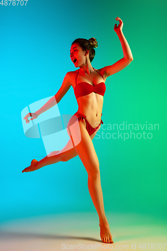 Image of Fashion portrait of seductive girl in stylish swimwear posing on a bright gradient background. Summertime, beach season