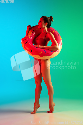 Image of Fashion portrait of seductive girl in stylish swimwear posing on a bright gradient background. Summertime, beach season