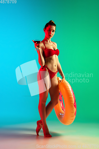 Image of Fashion portrait of seductive girl in stylish swimwear posing on a bright gradient background. Summertime, beach season