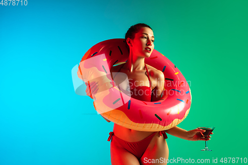 Image of Fashion portrait of seductive girl in stylish swimwear posing on a bright gradient background. Summertime, beach season