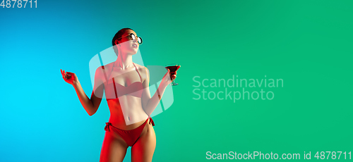 Image of Fashion portrait of seductive girl in stylish swimwear posing on a bright gradient background. Summertime, beach season