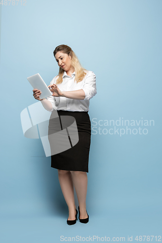 Image of Young caucasian woman in office attire on blue background. Bodypositive female character. plus size businesswoman