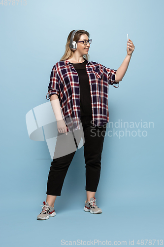 Image of Young caucasian woman in casual wear on blue background. Bodypositive female character, plus size businesswoman
