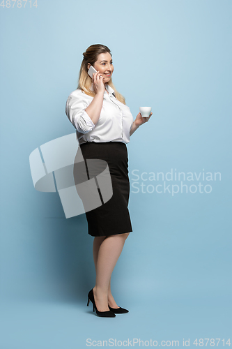 Image of Young caucasian woman in office attire on blue background. Bodypositive female character. plus size businesswoman