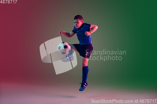 Image of Teen male football or soccer player, boy on gradient background in neon light - motion, action, activity concept