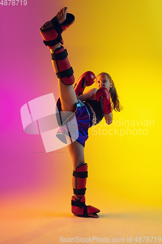 Image of Little caucasian female kick boxer training on gradient background in neon light, active and expressive