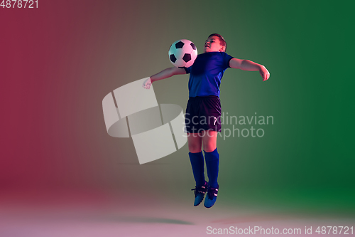Image of Teen male football or soccer player, boy on gradient background in neon light - motion, action, activity concept