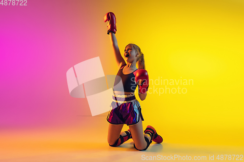 Image of Little caucasian female kick boxer training on gradient background in neon light, active and expressive