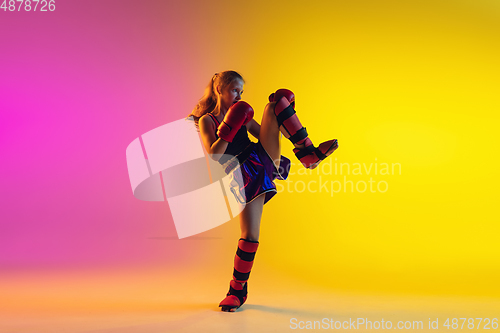 Image of Little caucasian female kick boxer training on gradient background in neon light, active and expressive