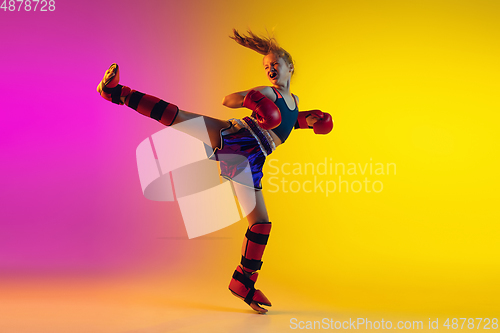 Image of Little caucasian female kick boxer training on gradient background in neon light, active and expressive