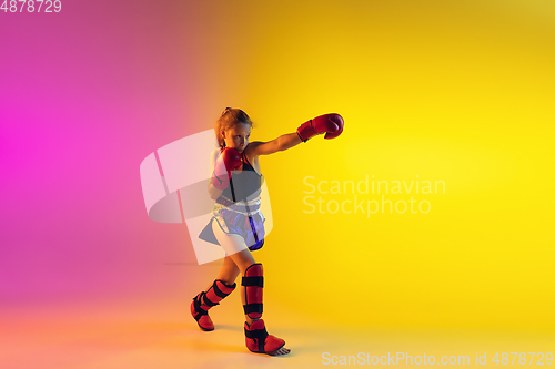 Image of Little caucasian female kick boxer training on gradient background in neon light, active and expressive