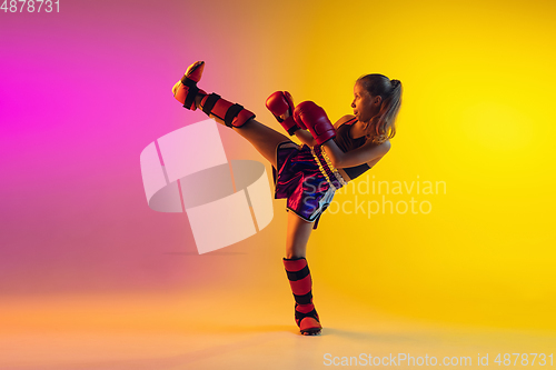 Image of Little caucasian female kick boxer training on gradient background in neon light, active and expressive