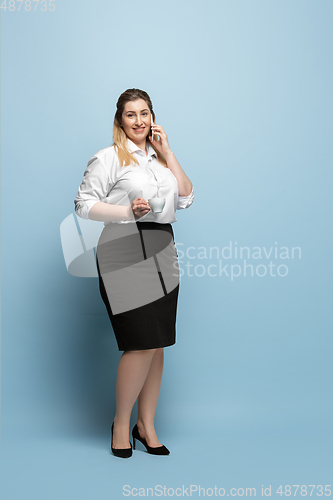 Image of Young caucasian woman in office attire on blue background. Bodypositive female character. plus size businesswoman