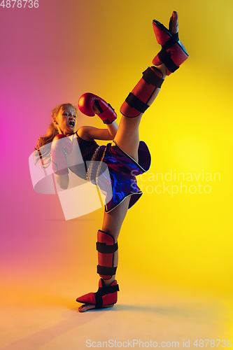 Image of Little caucasian female kick boxer training on gradient background in neon light, active and expressive