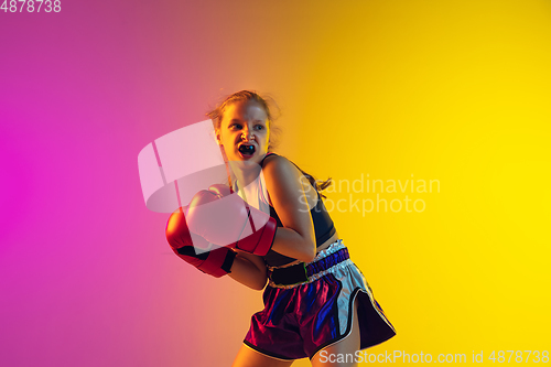 Image of Little caucasian female kick boxer training on gradient background in neon light, active and expressive