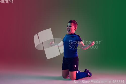 Image of Teen male football or soccer player, boy on gradient background in neon light - motion, action, activity concept