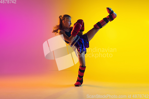 Image of Little caucasian female kick boxer training on gradient background in neon light, active and expressive