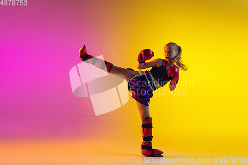 Image of Little caucasian female kick boxer training on gradient background in neon light, active and expressive