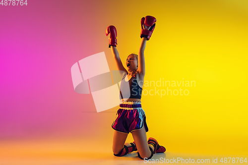 Image of Little caucasian female kick boxer training on gradient background in neon light, active and expressive