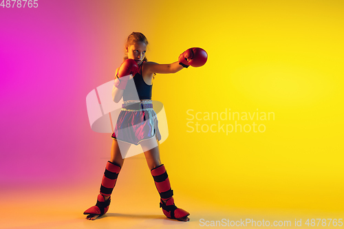 Image of Little caucasian female kick boxer training on gradient background in neon light, active and expressive