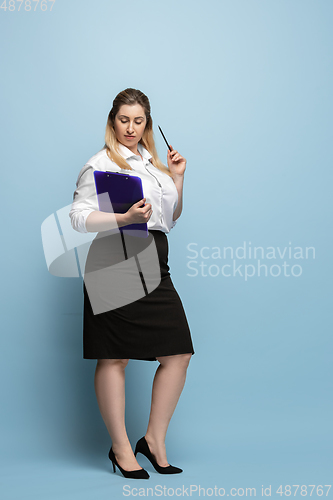 Image of Young caucasian woman in office attire on blue background. Bodypositive female character. plus size businesswoman