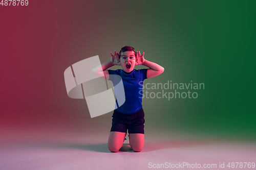 Image of Teen male football or soccer player, boy on gradient background in neon light - motion, action, activity concept