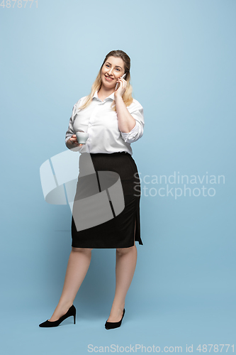 Image of Young caucasian woman in office attire on blue background. Bodypositive female character. plus size businesswoman