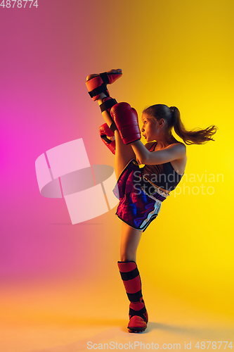 Image of Little caucasian female kick boxer training on gradient background in neon light, active and expressive