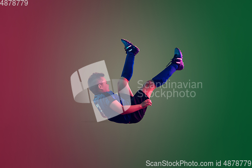Image of Teen male football or soccer player, boy on gradient background in neon light - motion, action, activity concept