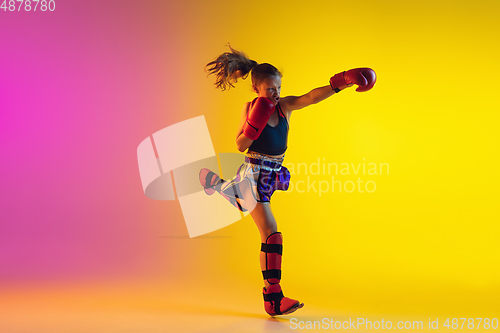 Image of Little caucasian female kick boxer training on gradient background in neon light, active and expressive