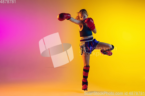 Image of Little caucasian female kick boxer training on gradient background in neon light, active and expressive