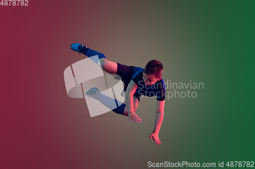 Image of Teen male football or soccer player, boy on gradient background in neon light - motion, action, activity concept