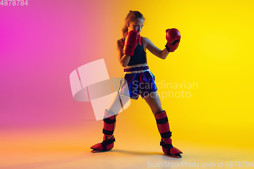 Image of Little caucasian female kick boxer training on gradient background in neon light, active and expressive