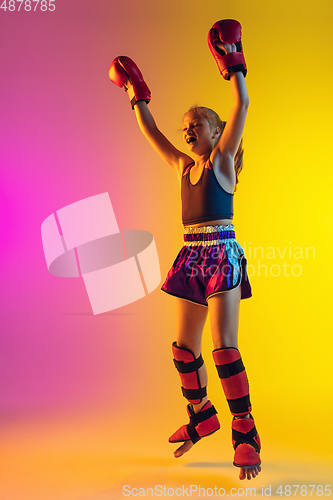 Image of Little caucasian female kick boxer training on gradient background in neon light, active and expressive