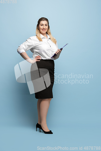 Image of Young caucasian woman in office attire on blue background. Bodypositive female character. plus size businesswoman