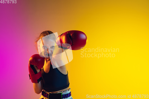 Image of Little caucasian female kick boxer training on gradient background in neon light, active and expressive