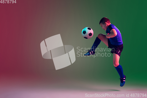 Image of Teen male football or soccer player, boy on gradient background in neon light - motion, action, activity concept