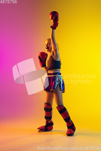 Image of Little caucasian female kick boxer training on gradient background in neon light, active and expressive