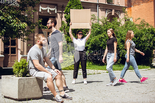 Image of Dude with sign - woman stands protesting things that annoy her